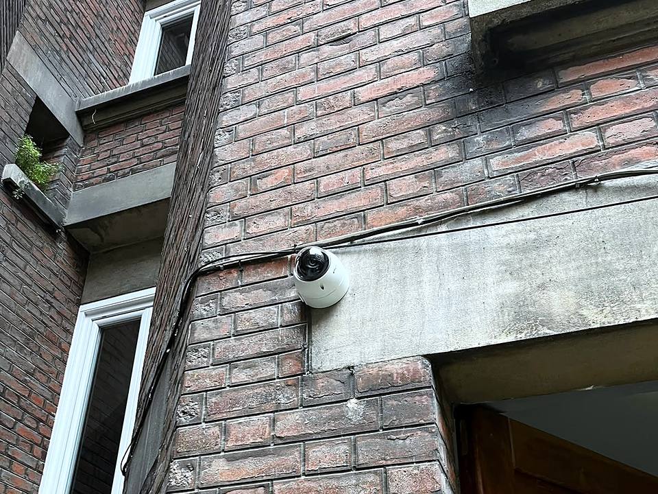 Caméra dôme posée sur le linteau d'une façade de brique