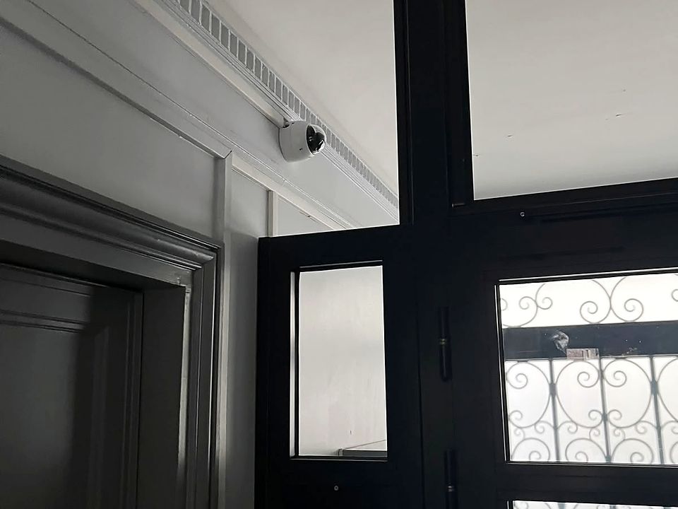 Porte d'entrée d'un hall d'immeuble, caméra dôme sous la corniche