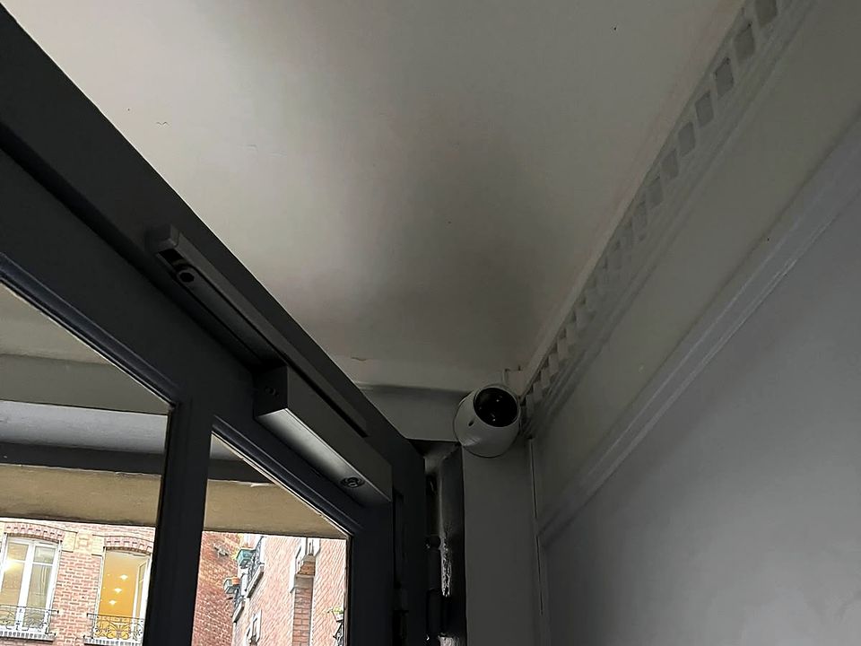 Caméra dôme en angle de plafond, près d'une ouverture sur cour
